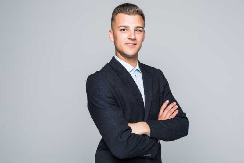 handsome-young-man-student-businessman-jacket-holds-his-arms-crossed-isolated-light-grey-wall-2.jpg